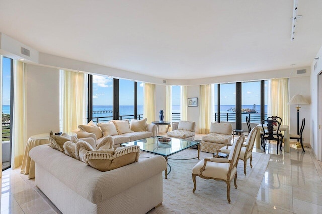 living room with expansive windows, light tile patterned flooring, a water view, and visible vents