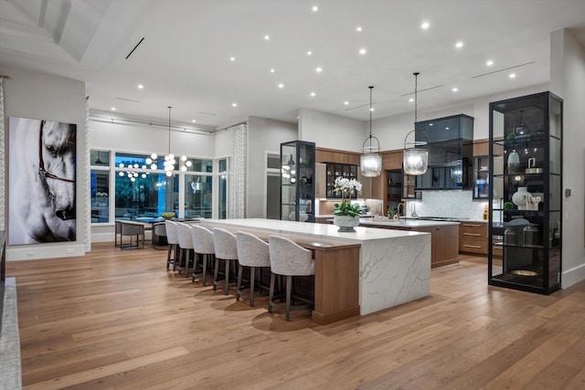 kitchen with decorative light fixtures, a spacious island, light stone countertops, and tasteful backsplash