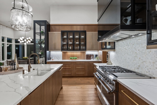 kitchen featuring decorative light fixtures, premium range hood, sink, and stainless steel range