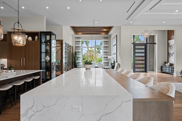 kitchen featuring a kitchen breakfast bar, dark wood-type flooring, light stone counters, and a large island