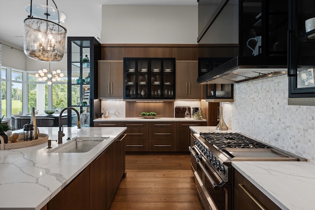 kitchen featuring stainless steel range, dark brown cabinetry, decorative light fixtures, and sink