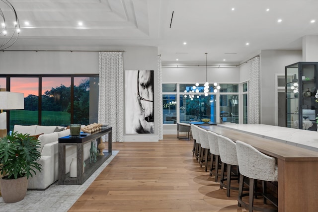 kitchen with light wood-type flooring, light stone countertops, hanging light fixtures, and an inviting chandelier