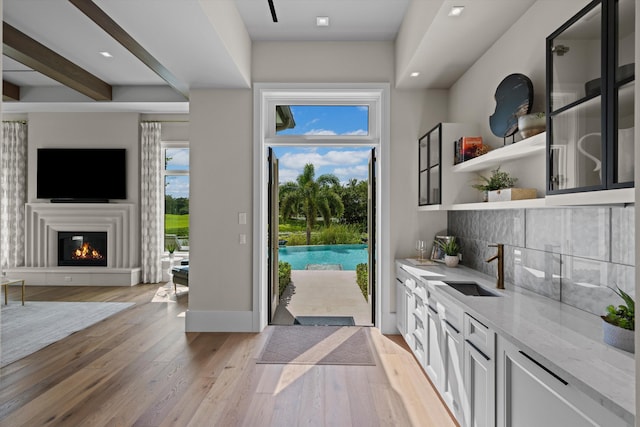 entryway with beamed ceiling, light hardwood / wood-style floors, and sink