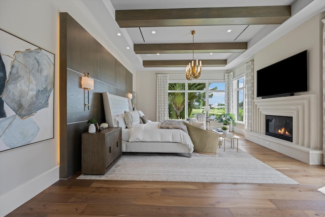 bedroom with a chandelier, beamed ceiling, and light hardwood / wood-style floors