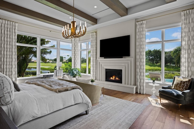 bedroom featuring multiple windows, hardwood / wood-style floors, beamed ceiling, and a chandelier