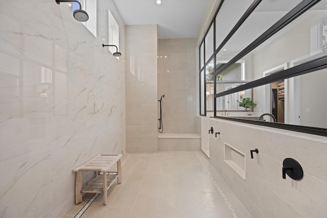 bathroom with plenty of natural light, a tile shower, and tile walls