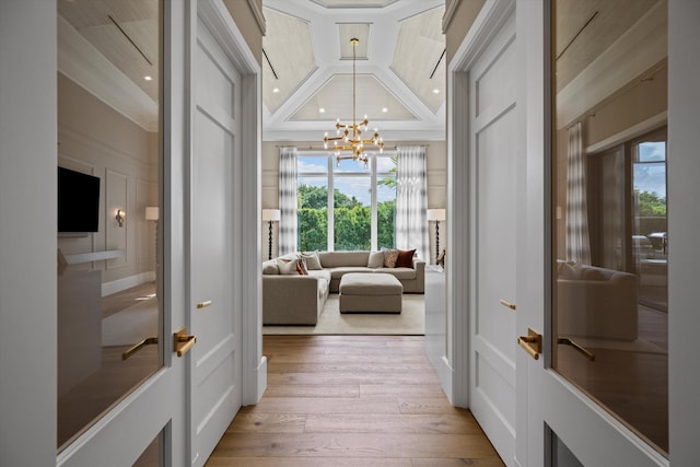 doorway featuring coffered ceiling, an inviting chandelier, beamed ceiling, light hardwood / wood-style floors, and ornamental molding