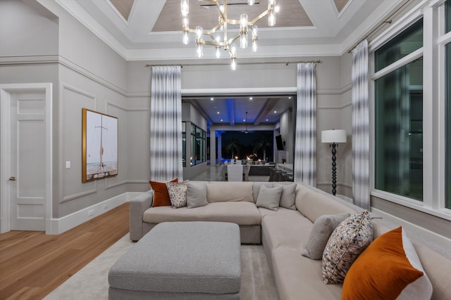 living room with an inviting chandelier, wood-type flooring, coffered ceiling, and ornamental molding