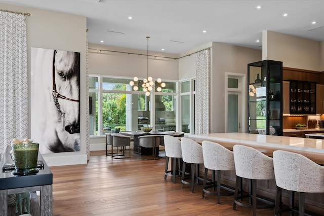 kitchen featuring hardwood / wood-style floors, hanging light fixtures, a notable chandelier, and a breakfast bar area