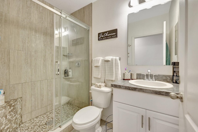 bathroom featuring vanity, a shower with shower door, and toilet