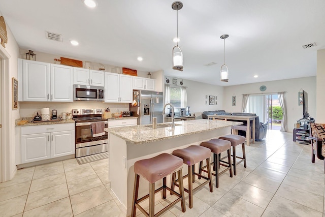 kitchen with white cabinetry, a center island with sink, decorative light fixtures, sink, and appliances with stainless steel finishes