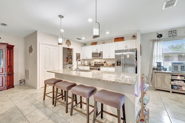 kitchen with appliances with stainless steel finishes, sink, hanging light fixtures, and white cabinets