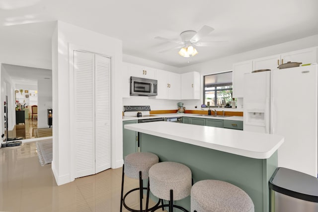 kitchen featuring white refrigerator with ice dispenser, a kitchen breakfast bar, sink, ceiling fan, and white cabinetry