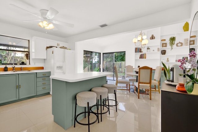 kitchen with plenty of natural light, white fridge with ice dispenser, ceiling fan with notable chandelier, and green cabinetry