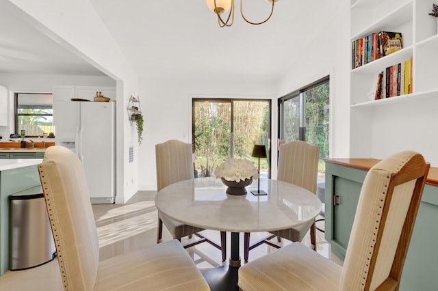 dining room featuring lofted ceiling, sink, and a chandelier