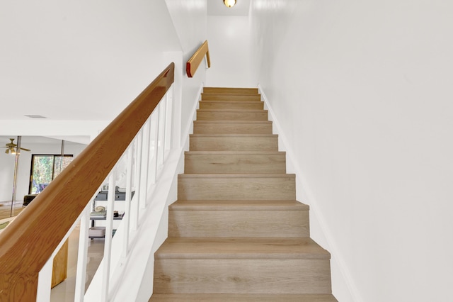 stairs featuring ceiling fan