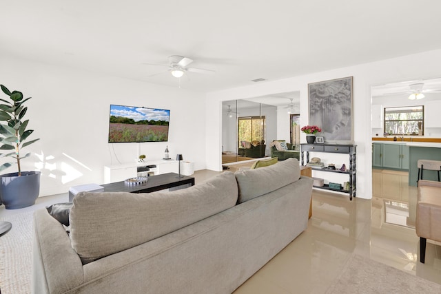 living room featuring ceiling fan, sink, and light tile patterned flooring