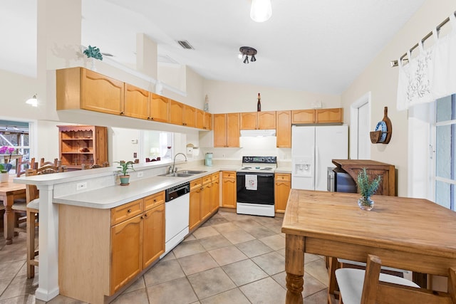 kitchen featuring white appliances, sink, light tile patterned floors, a kitchen bar, and kitchen peninsula