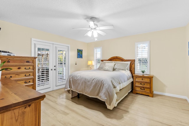 bedroom featuring access to outside, french doors, ceiling fan, light wood-type flooring, and multiple windows