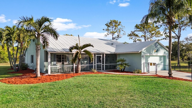 view of front of house featuring a sunroom, a garage, and a front yard