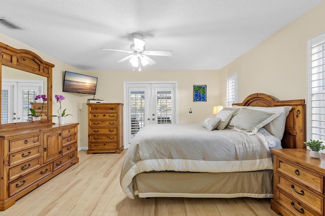 bedroom featuring access to exterior, ceiling fan, french doors, light hardwood / wood-style floors, and a textured ceiling