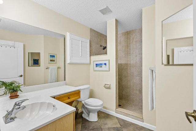 bathroom featuring tile patterned flooring, a textured ceiling, toilet, tiled shower, and vanity