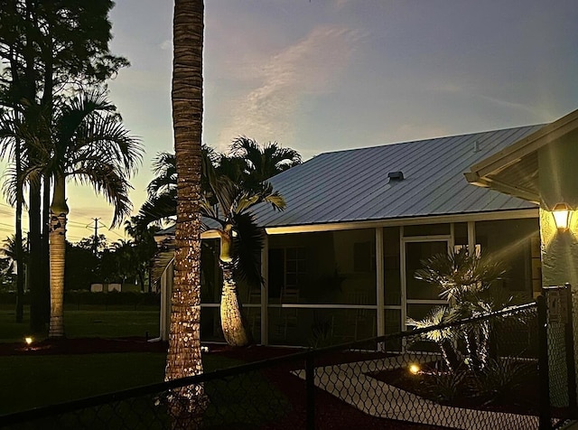 back house at dusk with a sunroom