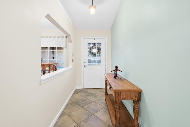 entryway with light tile patterned floors and ornamental molding