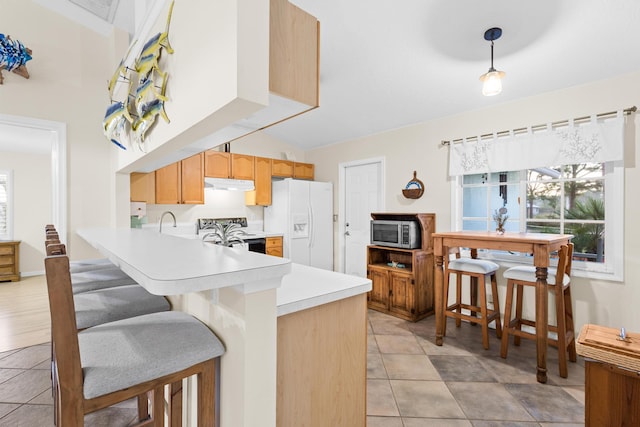 kitchen with kitchen peninsula, appliances with stainless steel finishes, a breakfast bar, and light tile patterned flooring