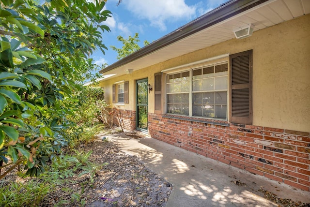 doorway to property with brick siding and stucco siding