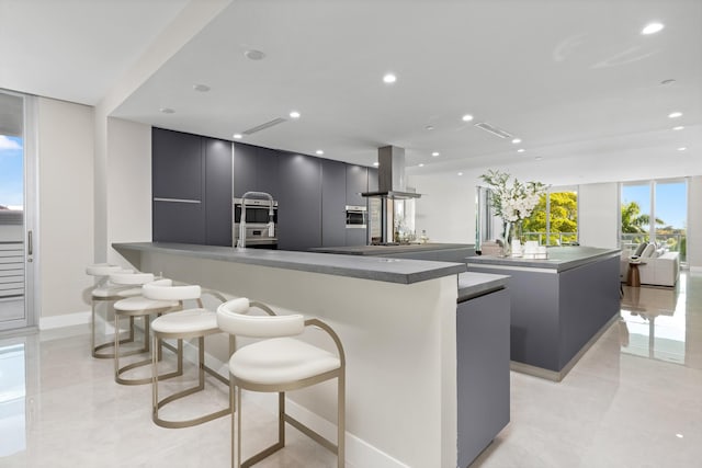 kitchen with a spacious island, kitchen peninsula, expansive windows, a breakfast bar area, and island range hood