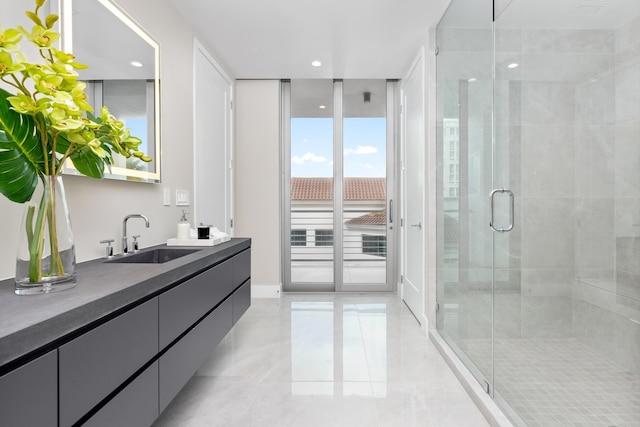 bathroom featuring a shower with shower door, a wall of windows, and vanity