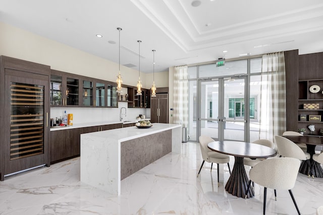 interior space featuring decorative light fixtures, dark brown cabinets, beverage cooler, expansive windows, and sink