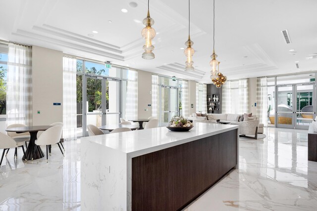 kitchen featuring floor to ceiling windows, a tray ceiling, french doors, hanging light fixtures, and a center island