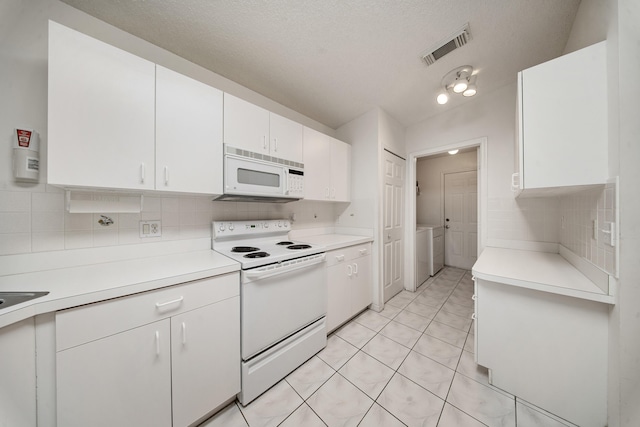 kitchen with decorative backsplash, white appliances, light tile patterned floors, washing machine and clothes dryer, and white cabinetry