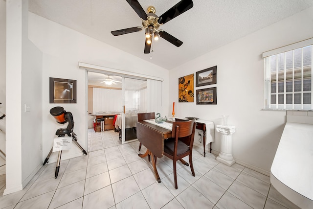 dining room with a textured ceiling, light tile patterned floors, and vaulted ceiling