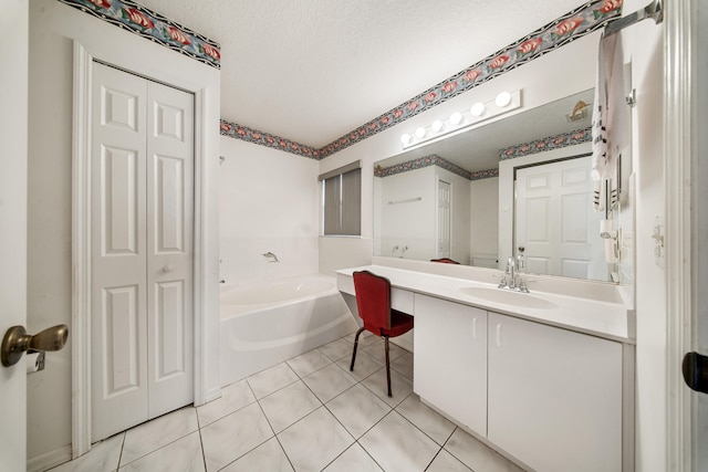 bathroom with tile patterned flooring, vanity, a tub to relax in, and a textured ceiling