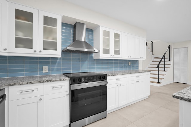 kitchen featuring tasteful backsplash, white cabinets, stainless steel appliances, and wall chimney range hood