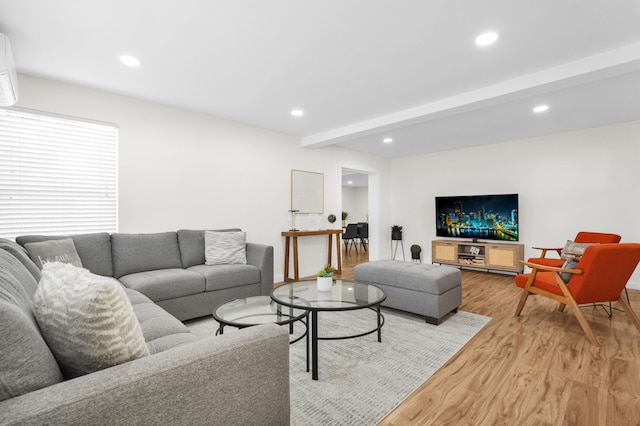 living room featuring beamed ceiling, a wall mounted air conditioner, and light wood-type flooring