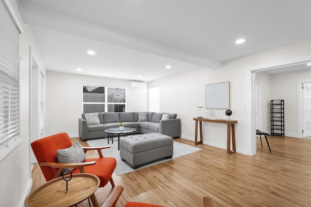 living room featuring beamed ceiling, light hardwood / wood-style floors, and a wall unit AC