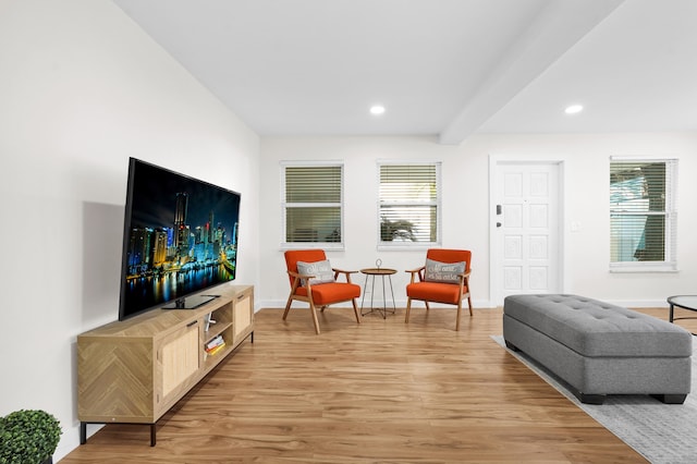 living area with beam ceiling and light hardwood / wood-style floors