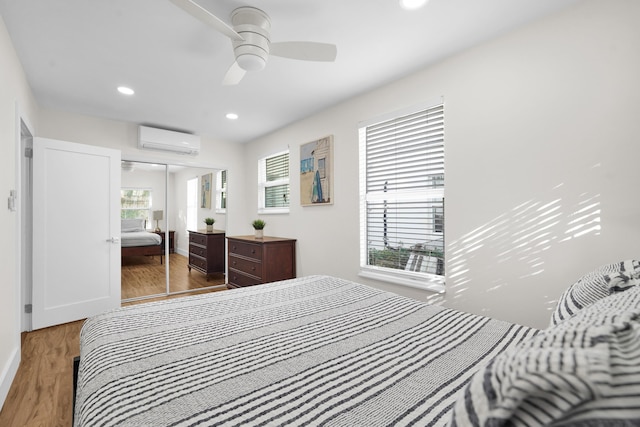 bedroom with ceiling fan, a closet, a wall mounted air conditioner, and hardwood / wood-style flooring