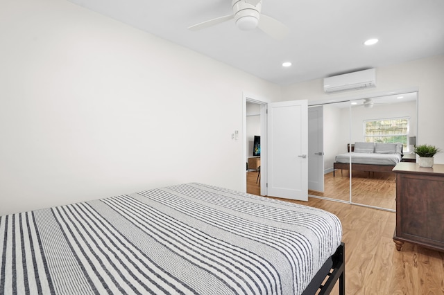 bedroom featuring ceiling fan, light hardwood / wood-style floors, a wall unit AC, and a closet