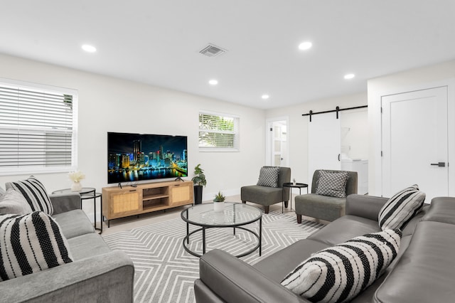 living room with a barn door and washer / dryer