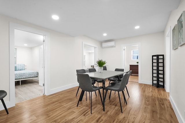 dining room featuring an AC wall unit and light hardwood / wood-style flooring