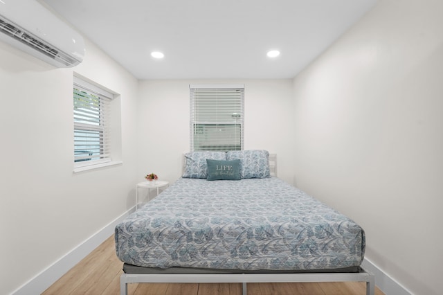 bedroom featuring hardwood / wood-style flooring and an AC wall unit