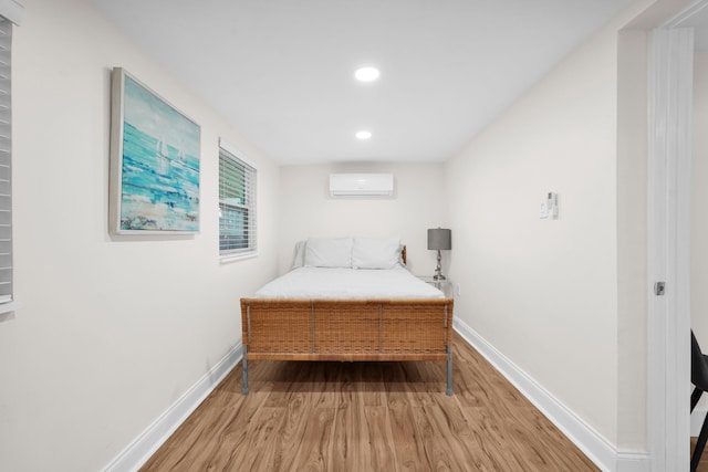 bedroom with hardwood / wood-style floors and a wall unit AC