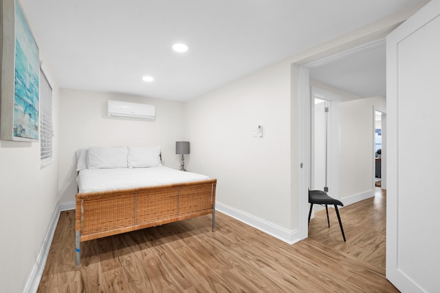 bedroom featuring hardwood / wood-style floors and a wall unit AC