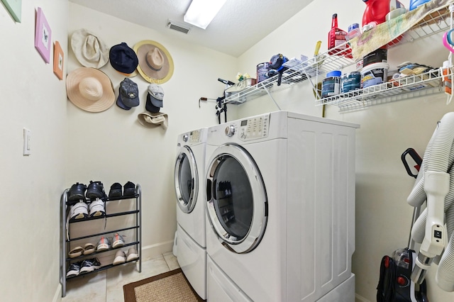 clothes washing area with independent washer and dryer and light tile patterned floors