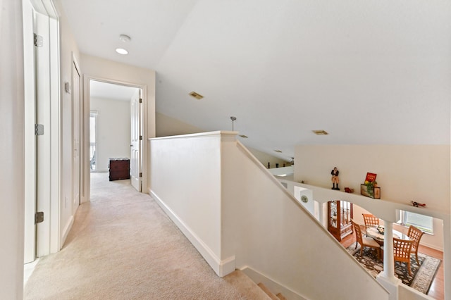 hall with light colored carpet and vaulted ceiling